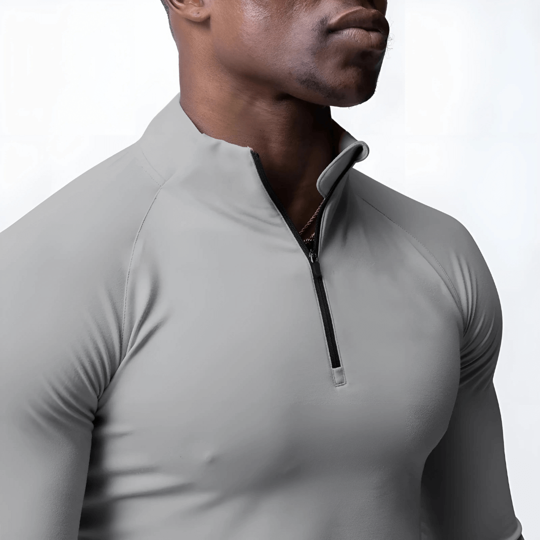 Close-up of a man wearing a gray Muscle V-Taper Quarter Zip performance top, showcasing its sleek design and zip collar.